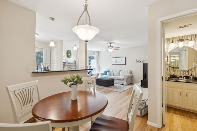 dining area featuring ceiling fan, sink, light wood-type flooring, and a healthy amount of sunlight