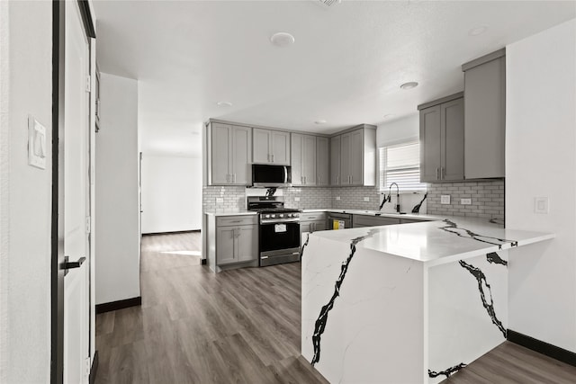 kitchen with gray cabinets, stainless steel appliances, dark hardwood / wood-style floors, and kitchen peninsula