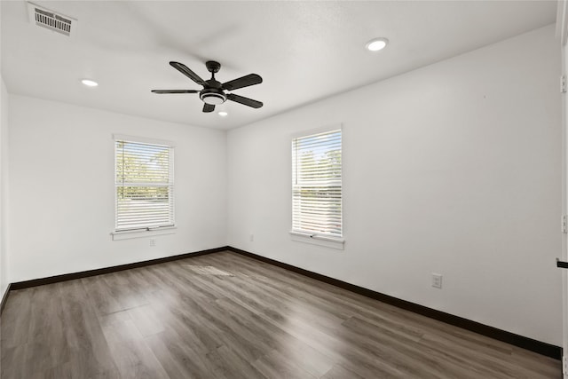 empty room featuring ceiling fan, a wealth of natural light, and dark wood-type flooring