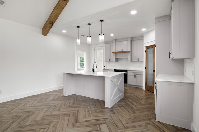 kitchen with beamed ceiling, parquet floors, stainless steel range oven, hanging light fixtures, and an island with sink