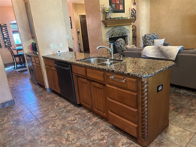 kitchen with black dishwasher, a brick fireplace, sink, and dark stone countertops