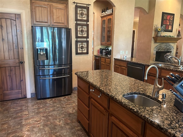 kitchen featuring dark stone counters, stainless steel refrigerator with ice dispenser, sink, and dishwasher