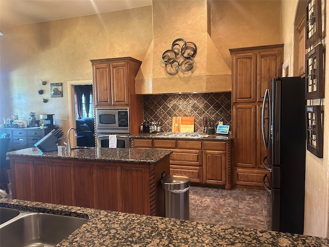 kitchen with sink, appliances with stainless steel finishes, tasteful backsplash, dark stone countertops, and custom exhaust hood