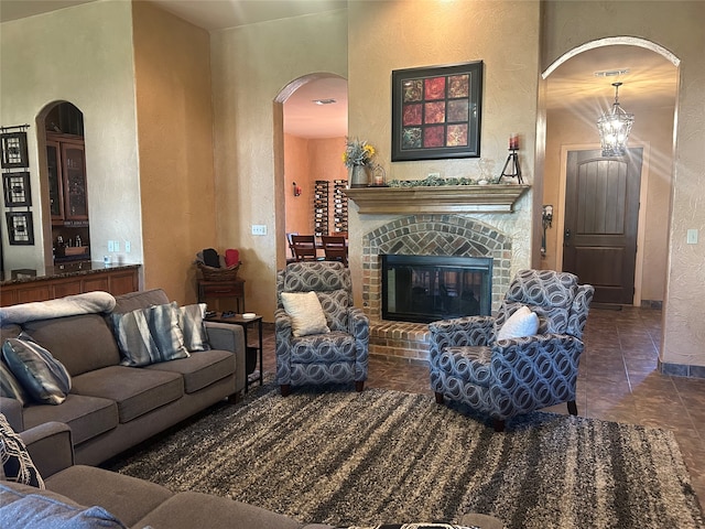 tiled living room featuring an inviting chandelier and a brick fireplace