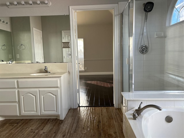 bathroom featuring vanity, wood-type flooring, and plus walk in shower