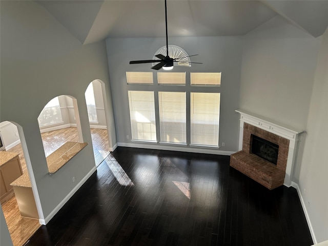 living room featuring ceiling fan, a fireplace, high vaulted ceiling, and dark hardwood / wood-style floors