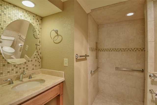 bathroom with vanity, toilet, ornamental molding, and a tile shower