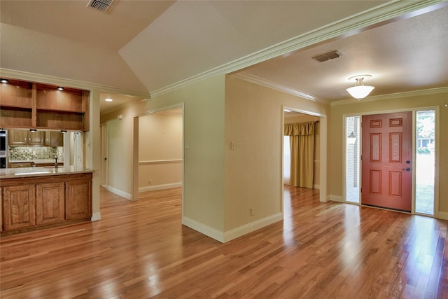 entrance foyer with crown molding, light hardwood / wood-style flooring, vaulted ceiling, and sink