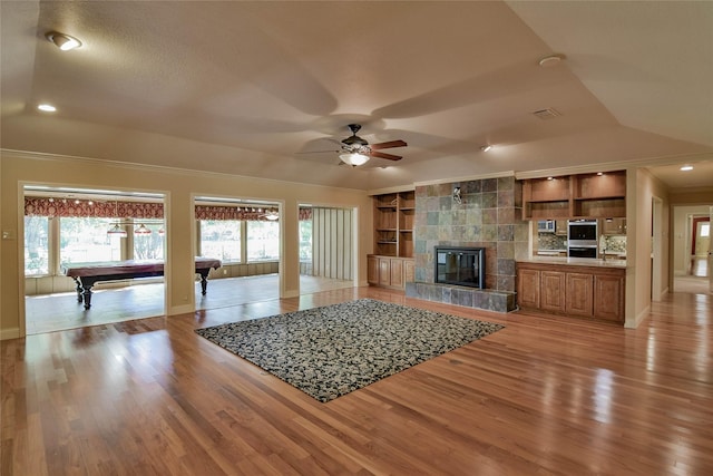 unfurnished living room with built in shelves, ceiling fan, pool table, and light hardwood / wood-style flooring