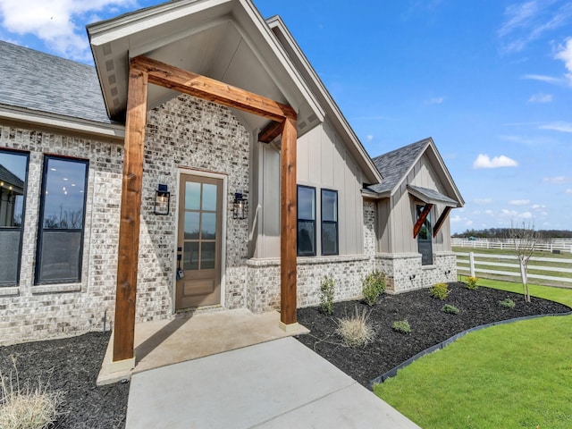 property entrance with board and batten siding, fence, and brick siding