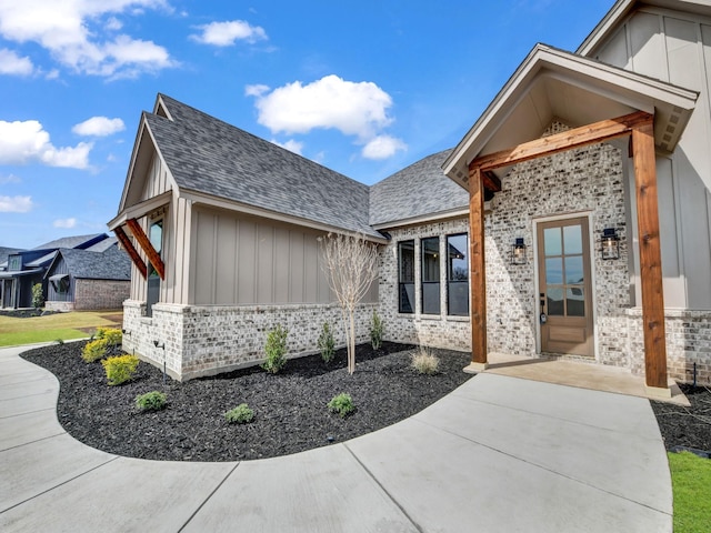 exterior space featuring brick siding, board and batten siding, and a shingled roof