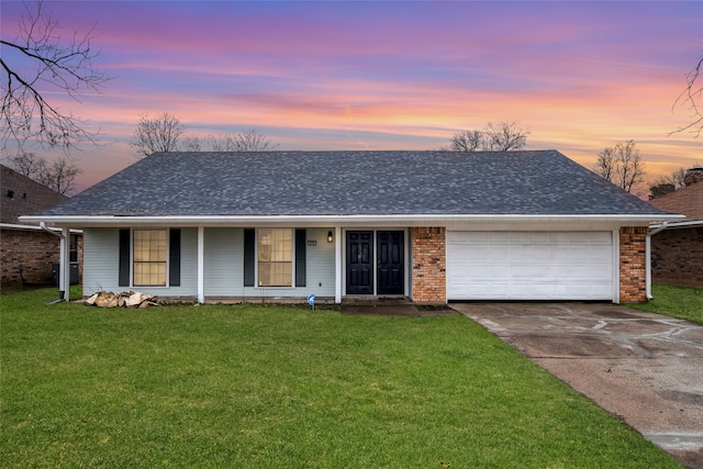 ranch-style home with covered porch, a lawn, and a garage