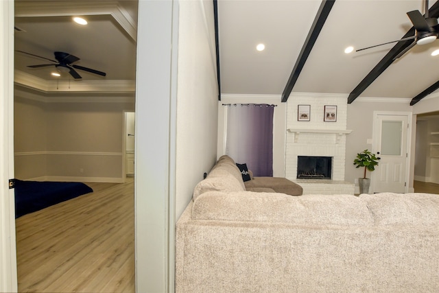 living room with ceiling fan, light hardwood / wood-style flooring, a fireplace, and crown molding