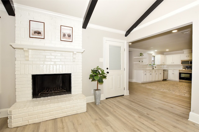 living room with light wood-type flooring, crown molding, sink, and a fireplace