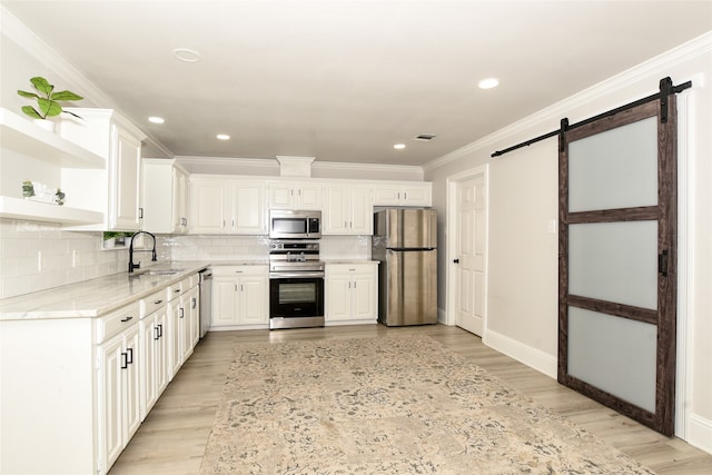 kitchen with a barn door, sink, stainless steel appliances, and light hardwood / wood-style flooring