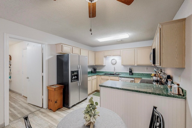 kitchen featuring light wood-type flooring, ceiling fan, stainless steel appliances, kitchen peninsula, and a textured ceiling