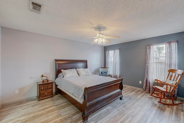 bedroom with a textured ceiling, light wood-type flooring, and ceiling fan