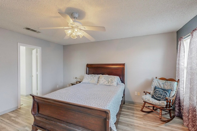 bedroom featuring light hardwood / wood-style flooring, a textured ceiling, and ceiling fan