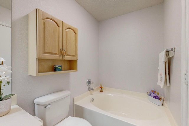 bathroom with a bath, a textured ceiling, and toilet