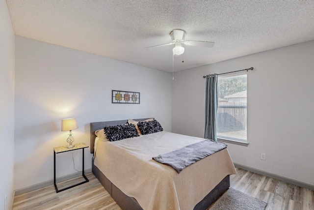 bedroom with ceiling fan, light hardwood / wood-style floors, and a textured ceiling