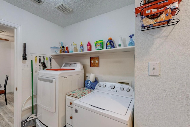 washroom featuring separate washer and dryer, light hardwood / wood-style floors, and a textured ceiling