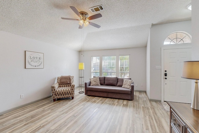 living room with ceiling fan, a textured ceiling, light hardwood / wood-style flooring, and a healthy amount of sunlight