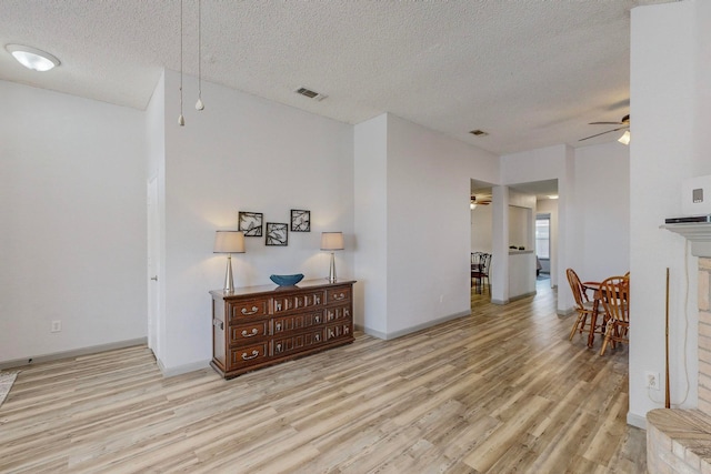 interior space featuring ceiling fan, a textured ceiling, and light wood-type flooring