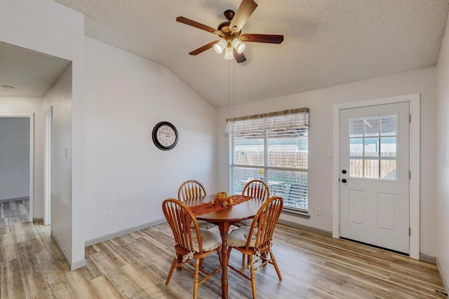 dining area featuring vaulted ceiling, light hardwood / wood-style flooring, a textured ceiling, and ceiling fan