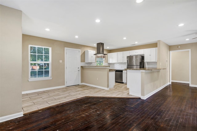 kitchen featuring ventilation hood, light hardwood / wood-style flooring, stainless steel appliances, kitchen peninsula, and white cabinets