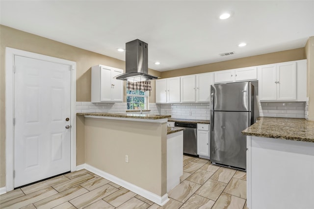 kitchen with appliances with stainless steel finishes, island range hood, light stone counters, and white cabinets