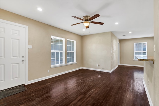 unfurnished living room featuring ceiling fan and dark wood-type flooring