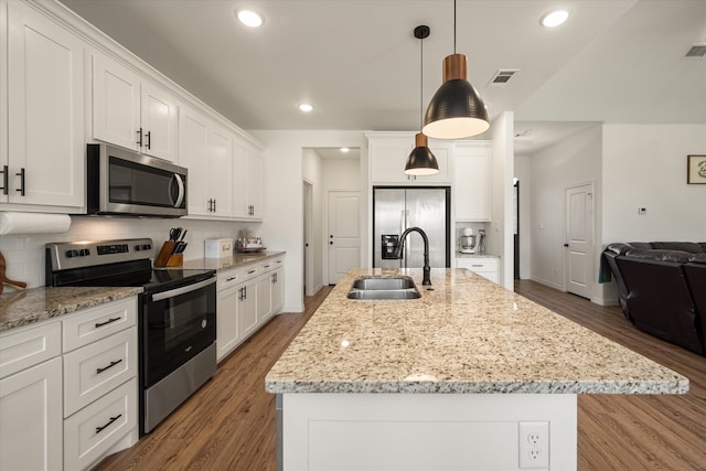 kitchen featuring appliances with stainless steel finishes, sink, a center island with sink, hardwood / wood-style floors, and hanging light fixtures