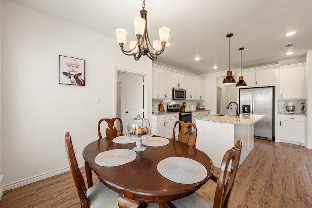 dining space featuring hardwood / wood-style flooring, a notable chandelier, and sink