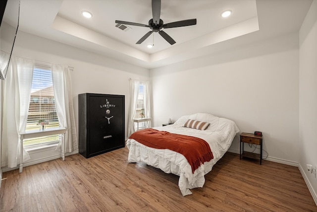 bedroom featuring hardwood / wood-style flooring, a raised ceiling, and ceiling fan