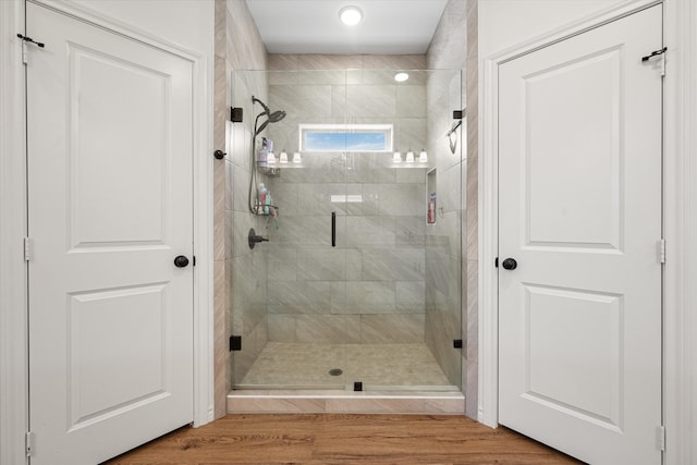 bathroom featuring a shower with shower door and wood-type flooring