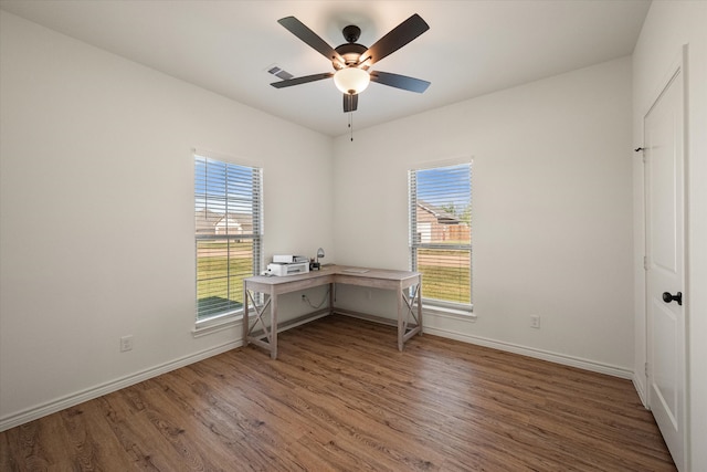 unfurnished office featuring ceiling fan, hardwood / wood-style floors, and a healthy amount of sunlight