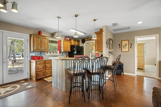 1455 County Road 2008 Unit B, Glen Rose, TX 76043 - kitchen featuring finished concrete floors, freestanding refrigerator, brown cabinets, healthy amount of natural light, and recessed lighting
