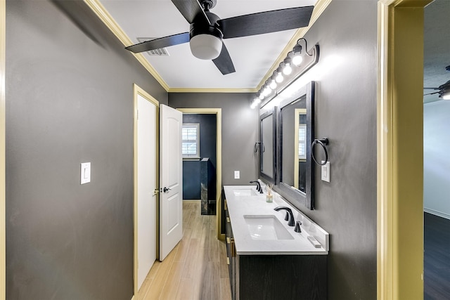 bathroom featuring wood finished floors, crown molding, a ceiling fan, and a sink