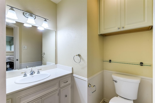 half bathroom featuring washer / clothes dryer, toilet, and vanity