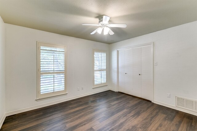 unfurnished bedroom with ceiling fan, dark hardwood / wood-style flooring, and a closet