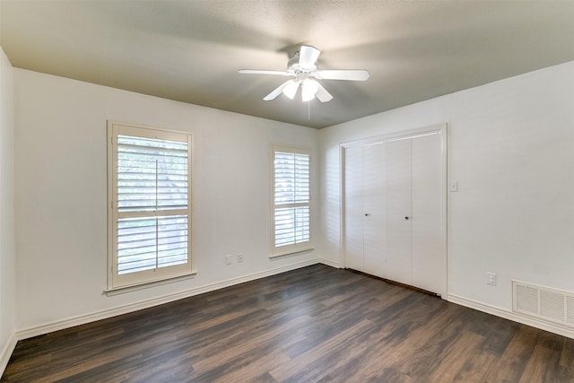 unfurnished bedroom featuring a closet, visible vents, dark wood-type flooring, and baseboards