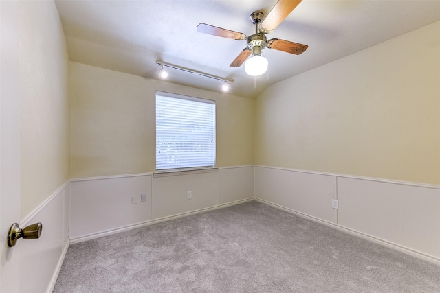 carpeted empty room featuring vaulted ceiling, rail lighting, and a ceiling fan