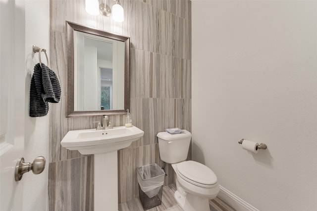 bathroom with sink, tile walls, and toilet