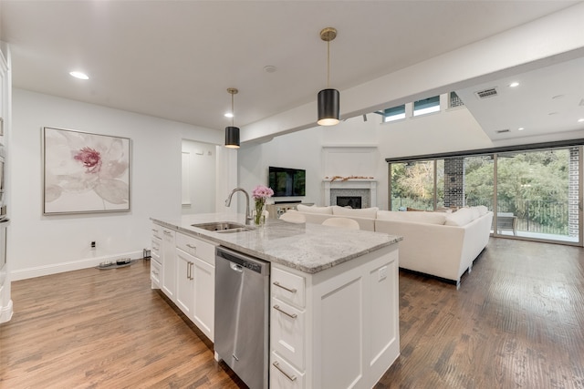 kitchen with white cabinets, sink, stainless steel dishwasher, decorative light fixtures, and hardwood / wood-style floors