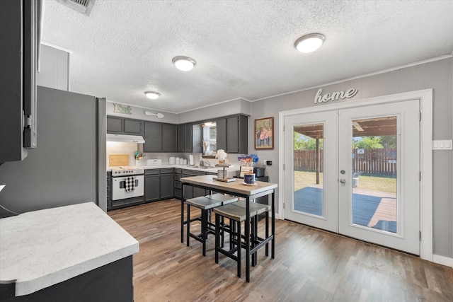 kitchen with a textured ceiling, white range oven, french doors, and light hardwood / wood-style flooring