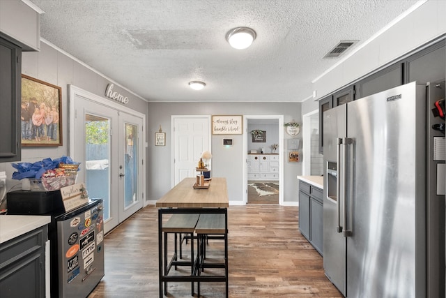 kitchen with a textured ceiling, wood-type flooring, gray cabinetry, french doors, and high end fridge