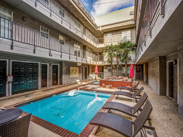 view of swimming pool featuring an in ground hot tub and a patio area