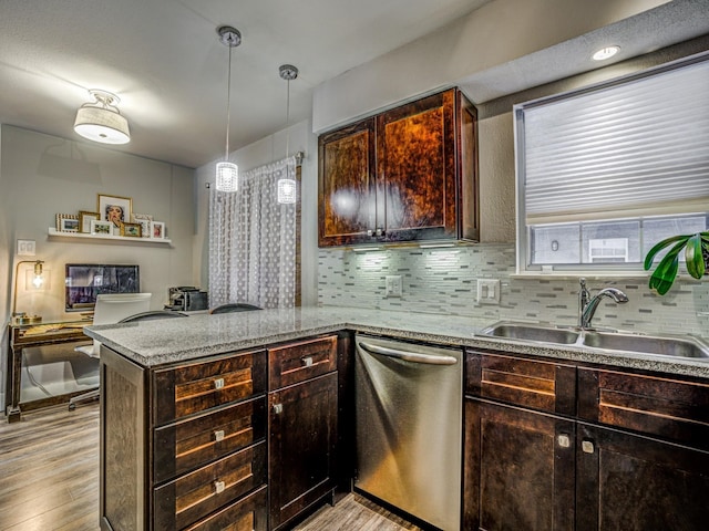 kitchen featuring light wood-type flooring, stainless steel dishwasher, sink, kitchen peninsula, and pendant lighting