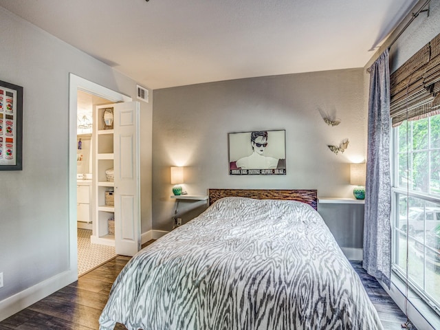 bedroom with ensuite bathroom and dark hardwood / wood-style floors