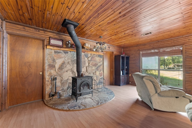 living room featuring light wood-type flooring, wood walls, wood ceiling, and a wood stove